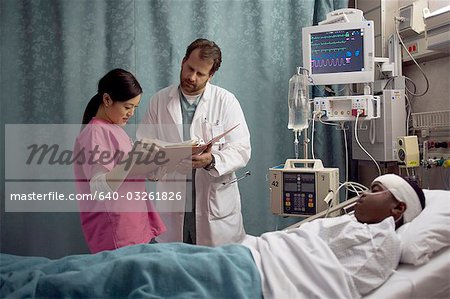 Doctor looking at medical chart of boy in hospital bed