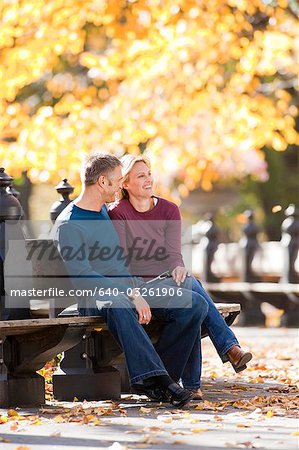 Couple sitting on wooden bench outdoors