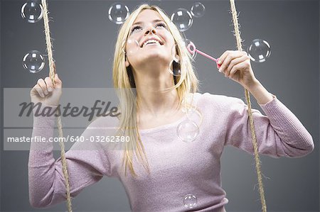 Woman blowing bubbles on swing