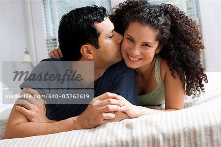 Man and woman on bed snuggling