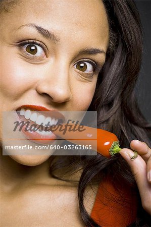 Woman with red lipstick eating red pepper