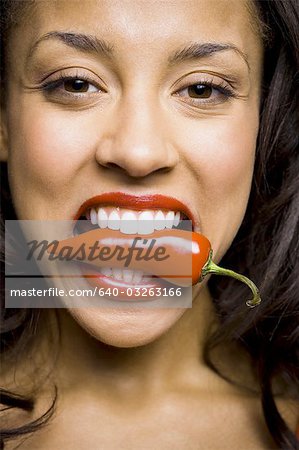 Woman with red lipstick eating red pepper