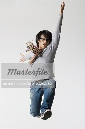 Man with eyeglasses leaping with arm up and closed fists