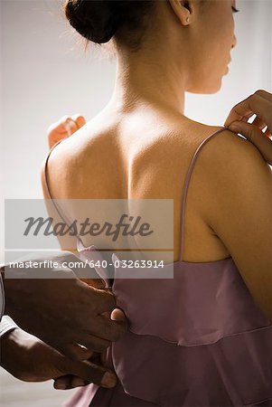 Man helping a woman with her dress zipper