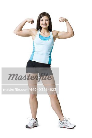 Woman flexing biceps and smiling - Stock Photo - Masterfile