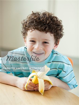 USA, Utah, Portrait of smiling boy (6-7) holding banana