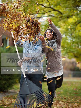 USA, Utah, Provo, Young woman throwing leaves over husband in garden