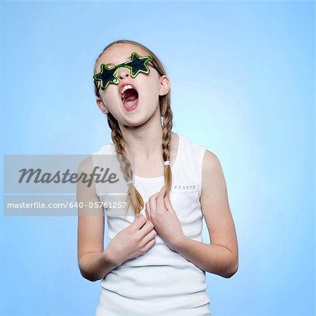 Studio portrait of girl (10-11) wearing star shaped glasses singing