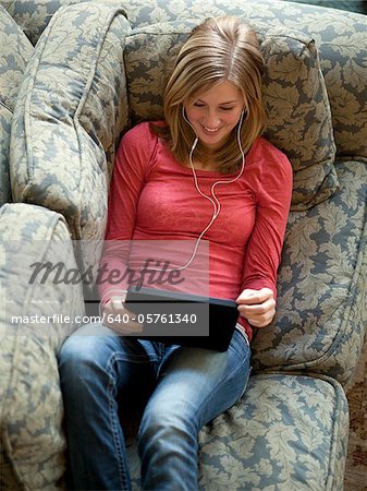 USA, Utah, Cedar Hills, Teenage girl (14-15) lying on listening to music from using digital tablet