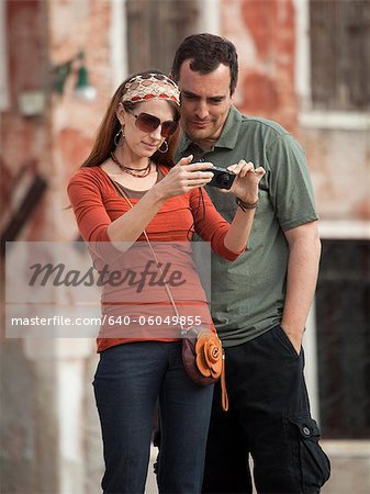 Italy, Venice, Couple viewing digital camera in city