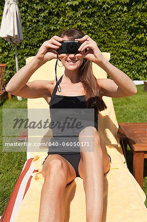 Italy, Amalfi Coast, Ravello, Mature woman taking picture while sitting on lounge chair