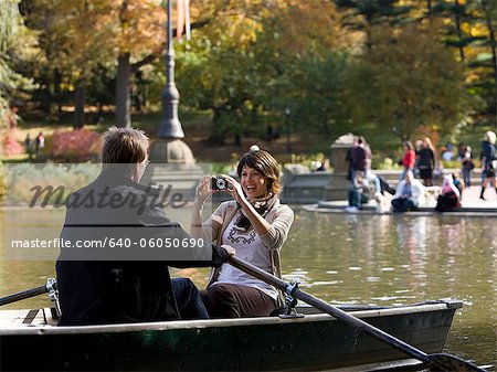 USA, New York City, Manhattan, Central Park, Mature woman photographing man in boat in Central Park