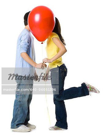 couple kissing behind a red balloon