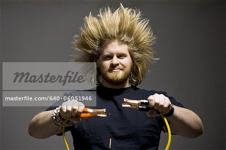 man with crazy hair holding jumper cables