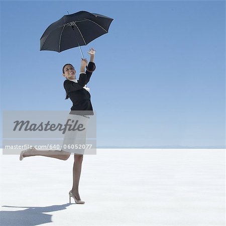 businesswoman holding an umbrella in the desert