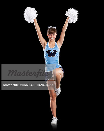 Portrait of teenage cheerleader girl (16-17) holding pom-poms