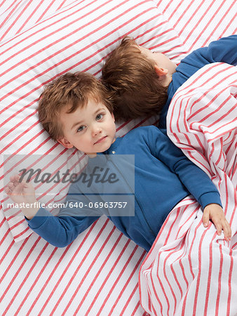 USA, Utah, Orem, Twin boys (2-3) wearing pajamas lying on bed