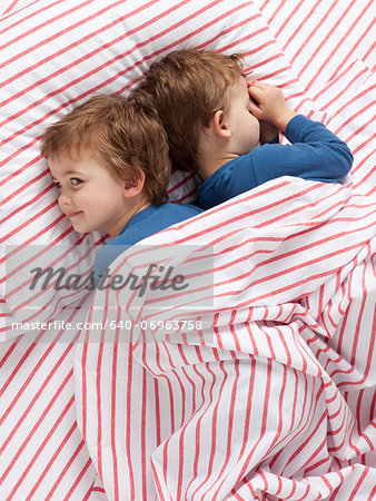 USA, Utah, Orem, Twin boys (2-3) wearing pajamas lying on bed