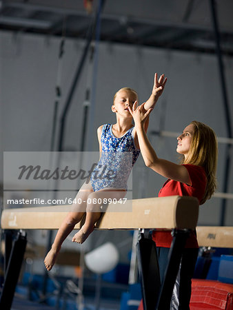USA, Utah, Orem, coach assisting girl gymnast (10-11) on balance beam