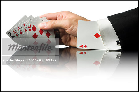 hand holding playing cards with an ace up his sleeve