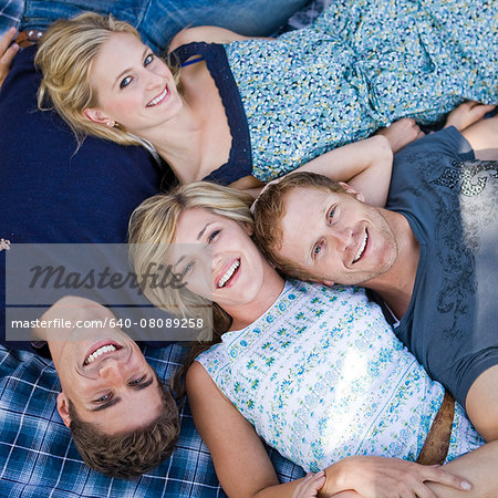 two couples lying on a picnic blanket