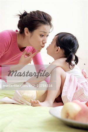 Mother and daughter sitting face to face and kissing