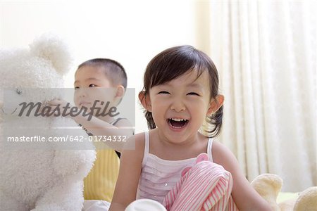 Close-up of a girl smiling while boy playing with toy