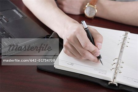 Businessman writing in a diary, close-up