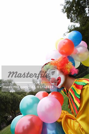 Clown holding various colors of balloons on lawn