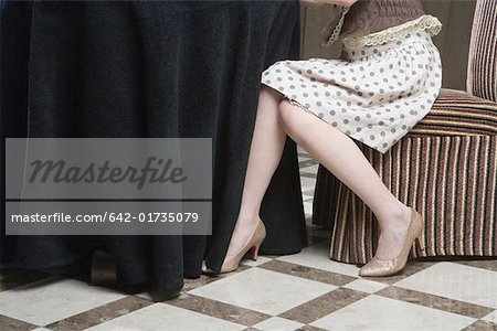 Woman sitting on chair, low section