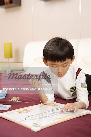 Boy lying on bed and painting