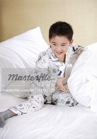 Boy playing with pillow on bed