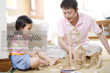 Father and daughter building a tower with wooden building blocks