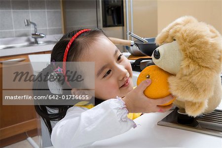 Girl feeding orange to doll