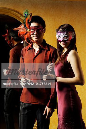 Young man and woman holding wineglass and wearing mask, portrait