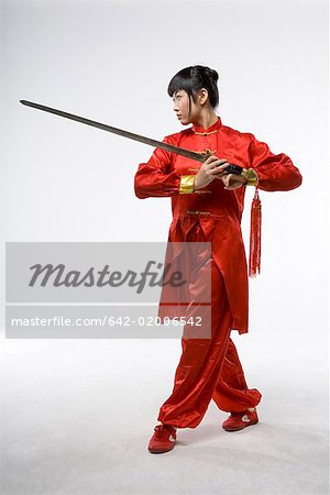 a woman in red dress practicing Chinese Kungfu with a sword