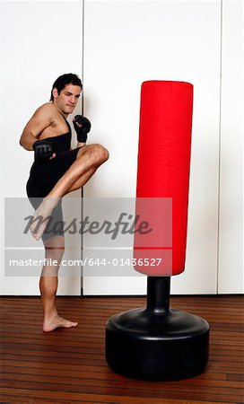 Young man kicking a punching bag