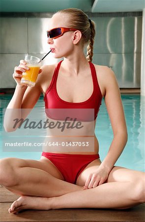 Young woman  drinking juice at spa pool