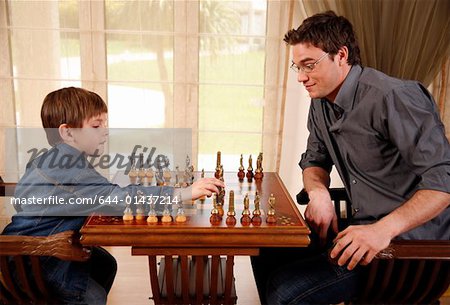 Young man and little boy playing chess