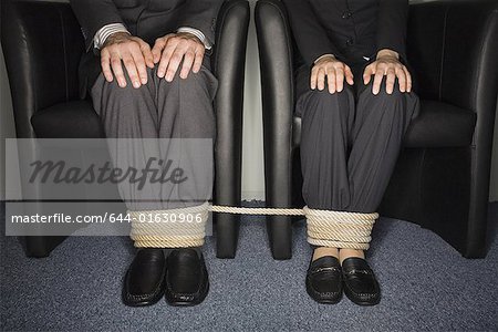 Male and female business people's legs tied