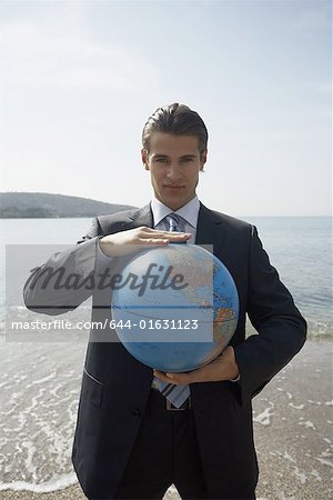 Businessman on beach with globe