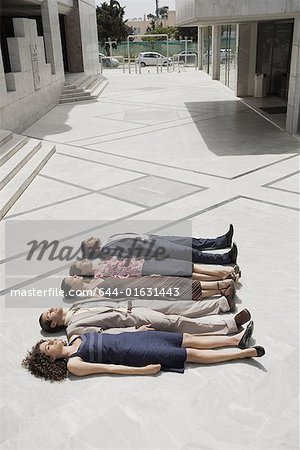 Business people lying on the ground in a row