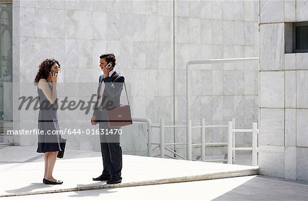 Businessman and businesswoman on cell phones meeting