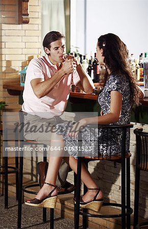 Couple in a bar, man lighting cigar