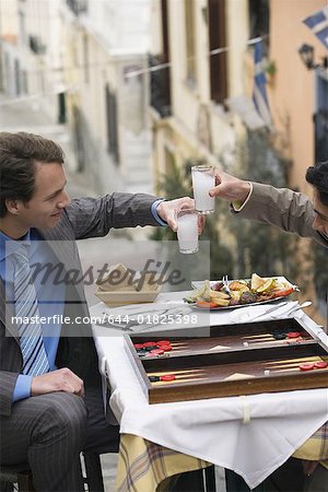 Businessmen at taverna with backgammon and ouzo