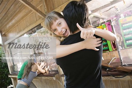 Teenage couple hugging at game in amusement park