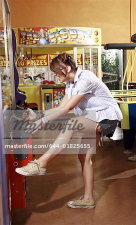 Female teenager playing game in amusement park arcade