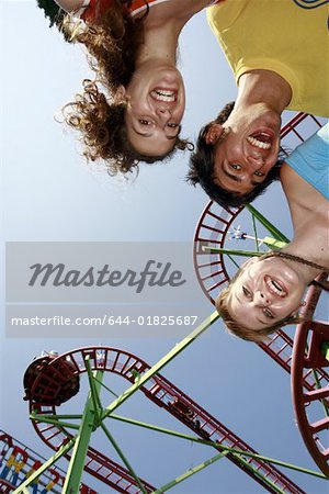 Teenagers posing at roller coaster at amusement park