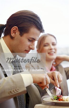 Businessman eating with businesswoman