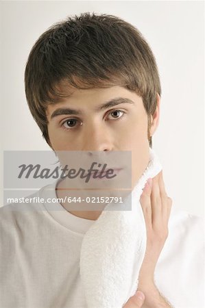 Young male adult drying chin with towel